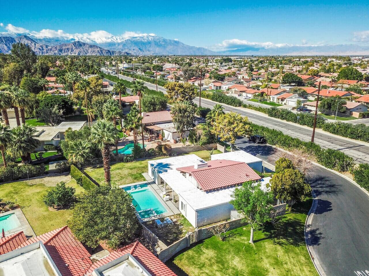A residential area with houses, a swimming pool, and a mountain range in the background.