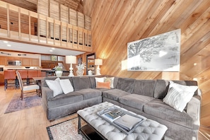 Una sala de estar moderna con un sofá modular, una mesa de centro y un comedor con sillas y una mesa.