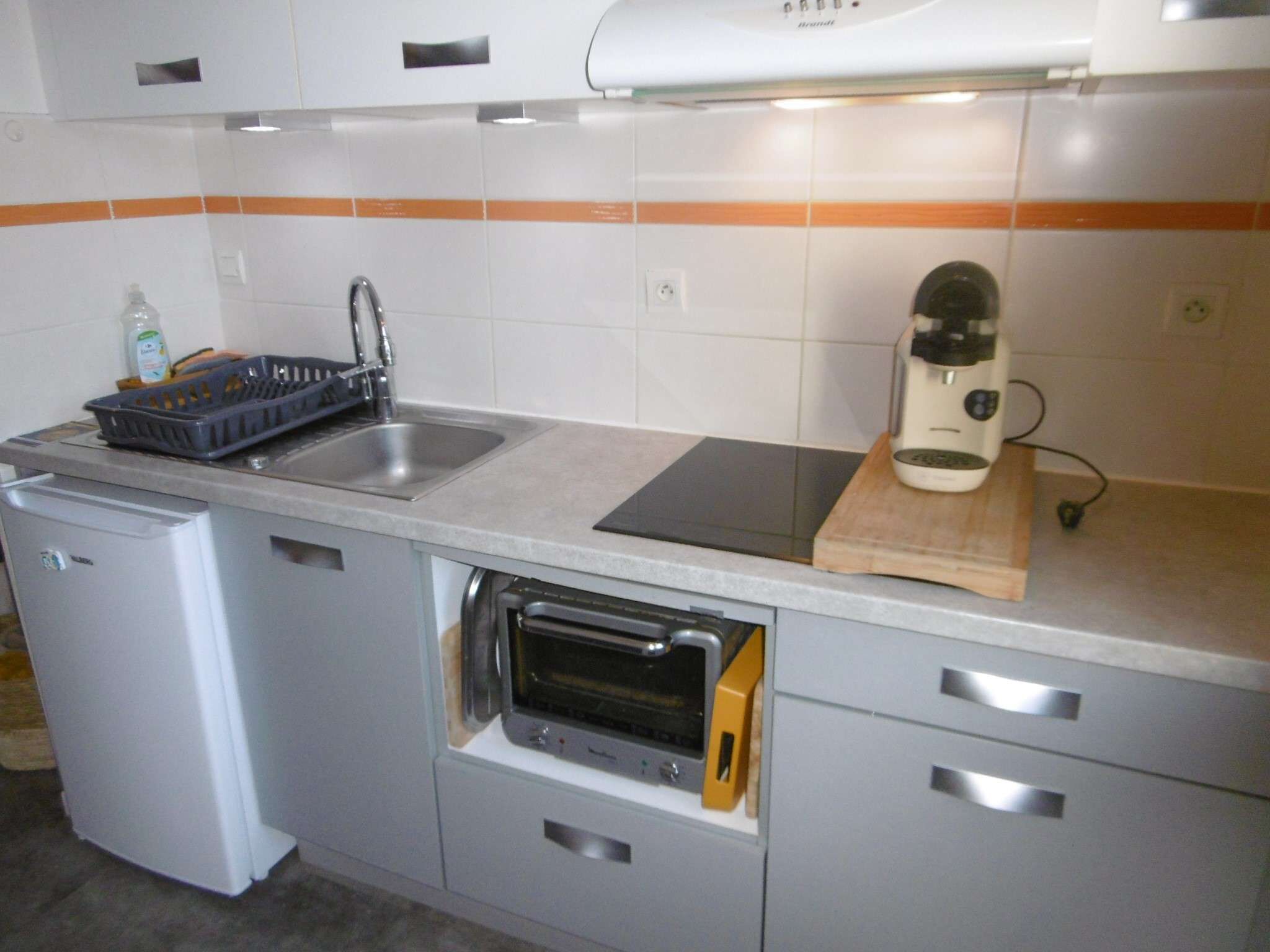 A compact kitchen with a built-in dishwasher, a toaster, and a microwave.