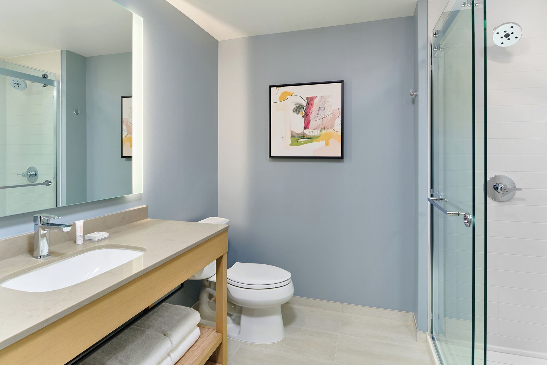 Un baño con ducha de vidrio, lavamanos e inodoro.