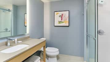 Un baño con ducha de vidrio, lavamanos e inodoro.