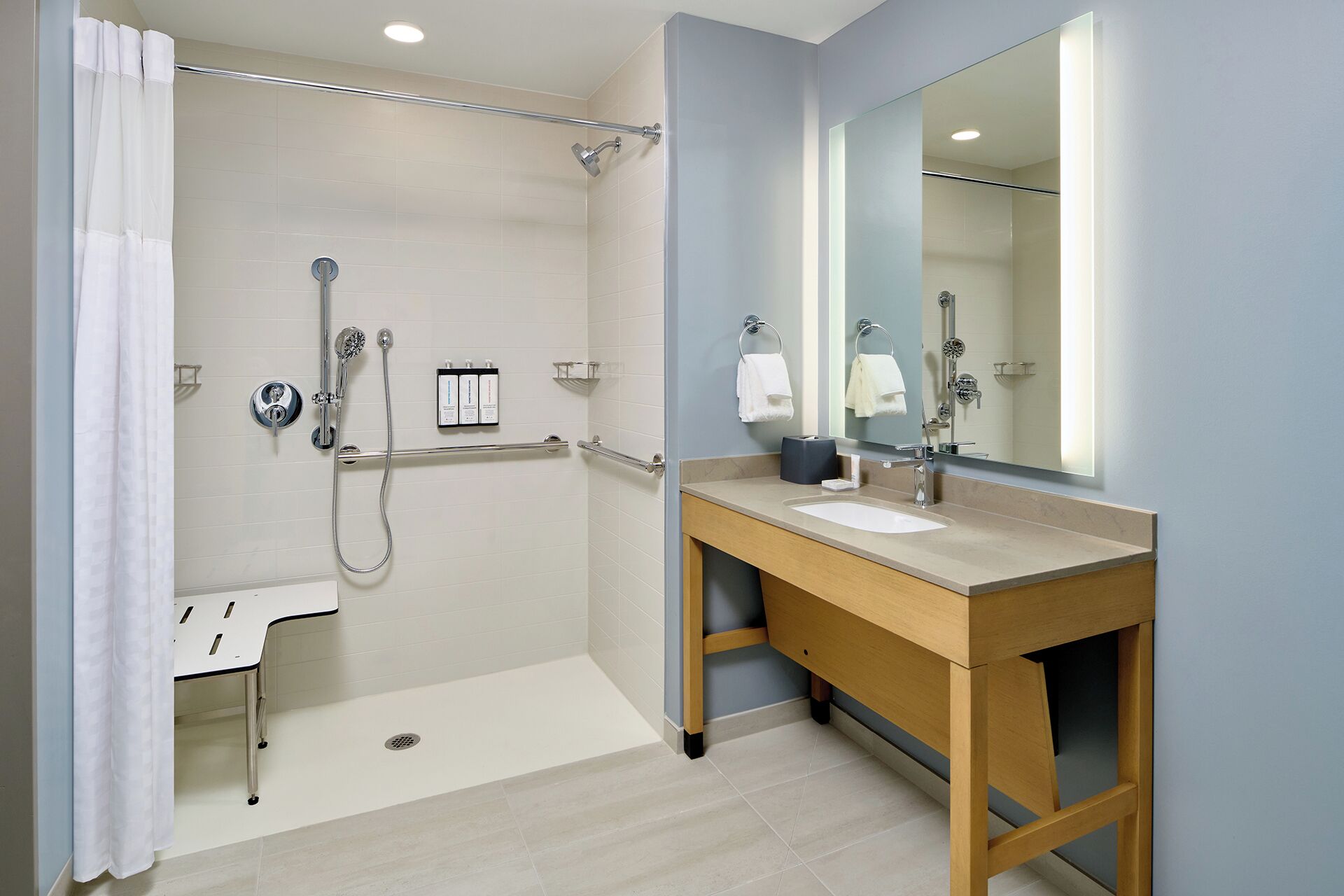 A modern bathroom with a walk-in shower, a vanity with a sink, and a large mirror.