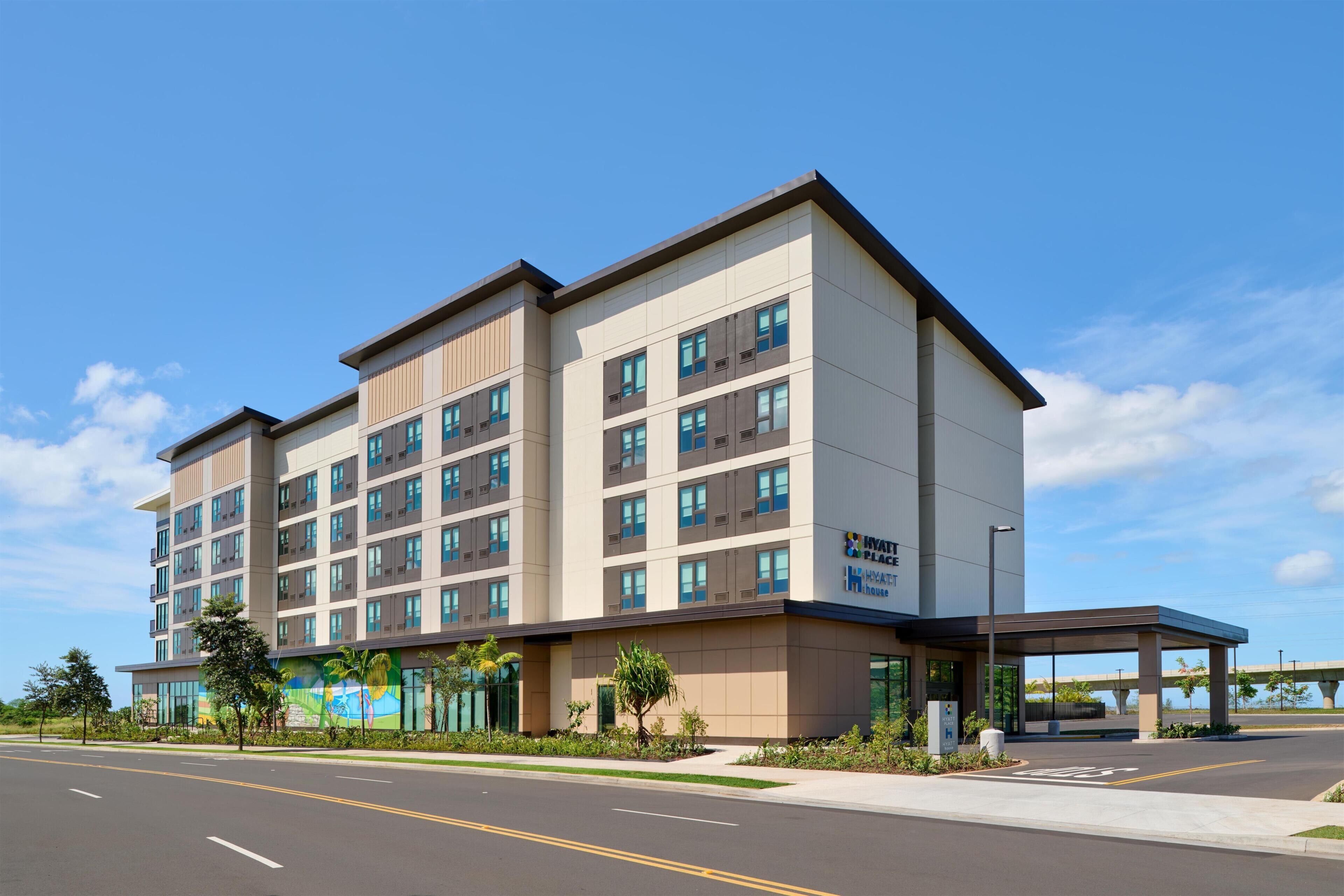 A multi-story hotel with a flat roof, large windows, and a covered entrance area.
