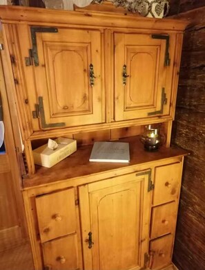 Ein Holzkabinent mit zwei Türen und einer Ablage, darin ein Taschentuchgehäuse und ein Buch.