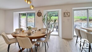 A dining area with a round table, chairs, and a potted plant. - Le refuge du Mesnil - MESNIL-ROC'H (MESNIL-ROC'H)