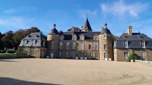 A large, historic stone building with multiple towers and a central spire, surrounded by a spacious courtyard. - Le refuge du Mesnil - MESNIL-ROC'H (MESNIL-ROC'H)