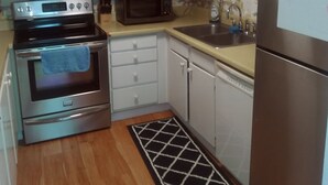 A compact kitchen with white cabinets, a stainless steel oven, a microwave, a sink, and a refrigerator. - Direct Oceanfront Balcony, 23rd Floor, Peck Plaza Building, Daytona Beach Shores (Daytona Beach Shores)