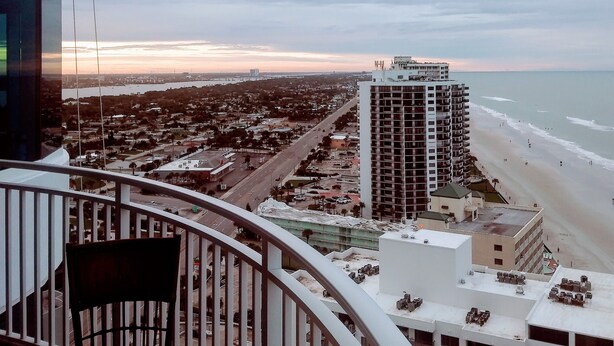 A balcony with a view of a beach, a cityscape, and a tall building. - Direct Oceanfront Balcony, 23rd Floor, Peck Plaza Building, Daytona Beach Shores (Daytona Beach Shores)