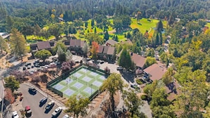 An aerial view of a residential area with multiple houses, a tennis court, and surrounding greenery. - Game Room, 8 guests- Lake, Yosemite, Sonora nearby (Groveland)