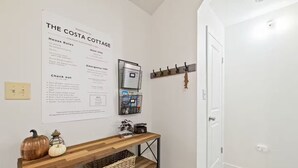 A clean hallway with a welcome sign for The Costa Cottages, a wooden console table with a basket, and a door to the right. - Game Room, 8 guests- Lake, Yosemite, Sonora nearby (Groveland)