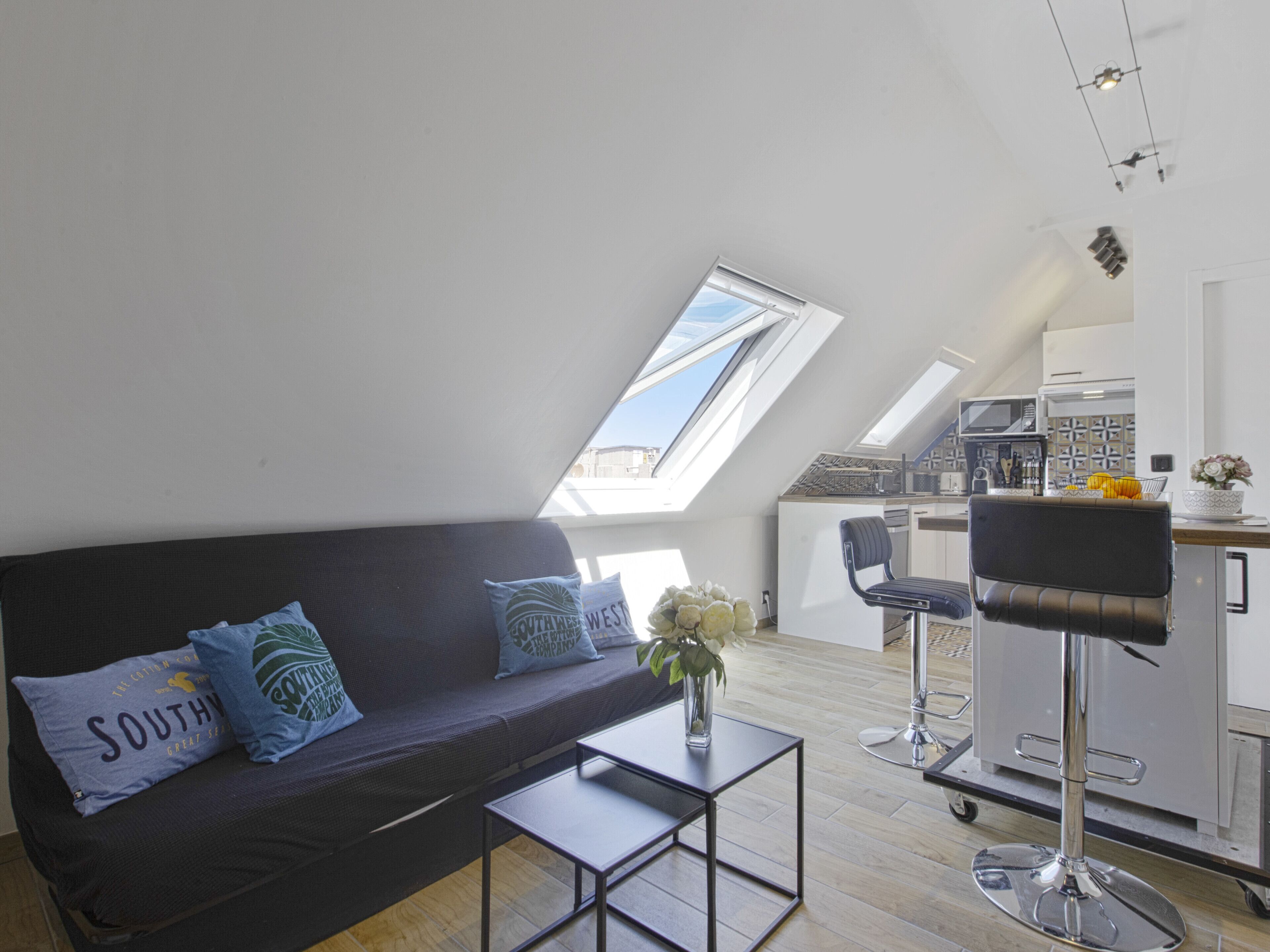 Een modern loft appartement met hoge plafonds, dakraam en een kitchenette.