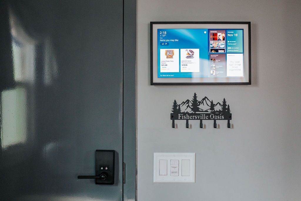 A digital display with a clock, temperature, and a list of items you may like. Below it, there's a sign with a mountain and tree silhouette and the text "Fishersville Oasis."