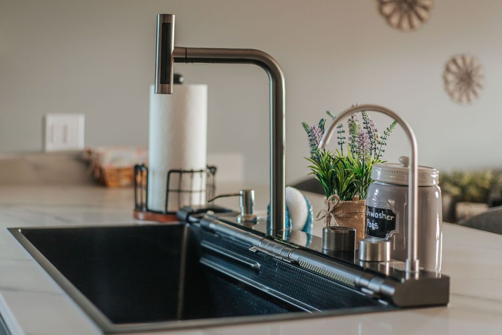 A kitchen with a modern faucet, a soap dispenser, and a small potted plant on the counter.