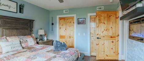 A bedroom with a bed, a nightstand, a lamp, a ceiling fan, and wooden doors.
