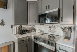 Cozinha moderna com eletrodomésticos de aço inoxidável, micro-ondas e máquina de café.