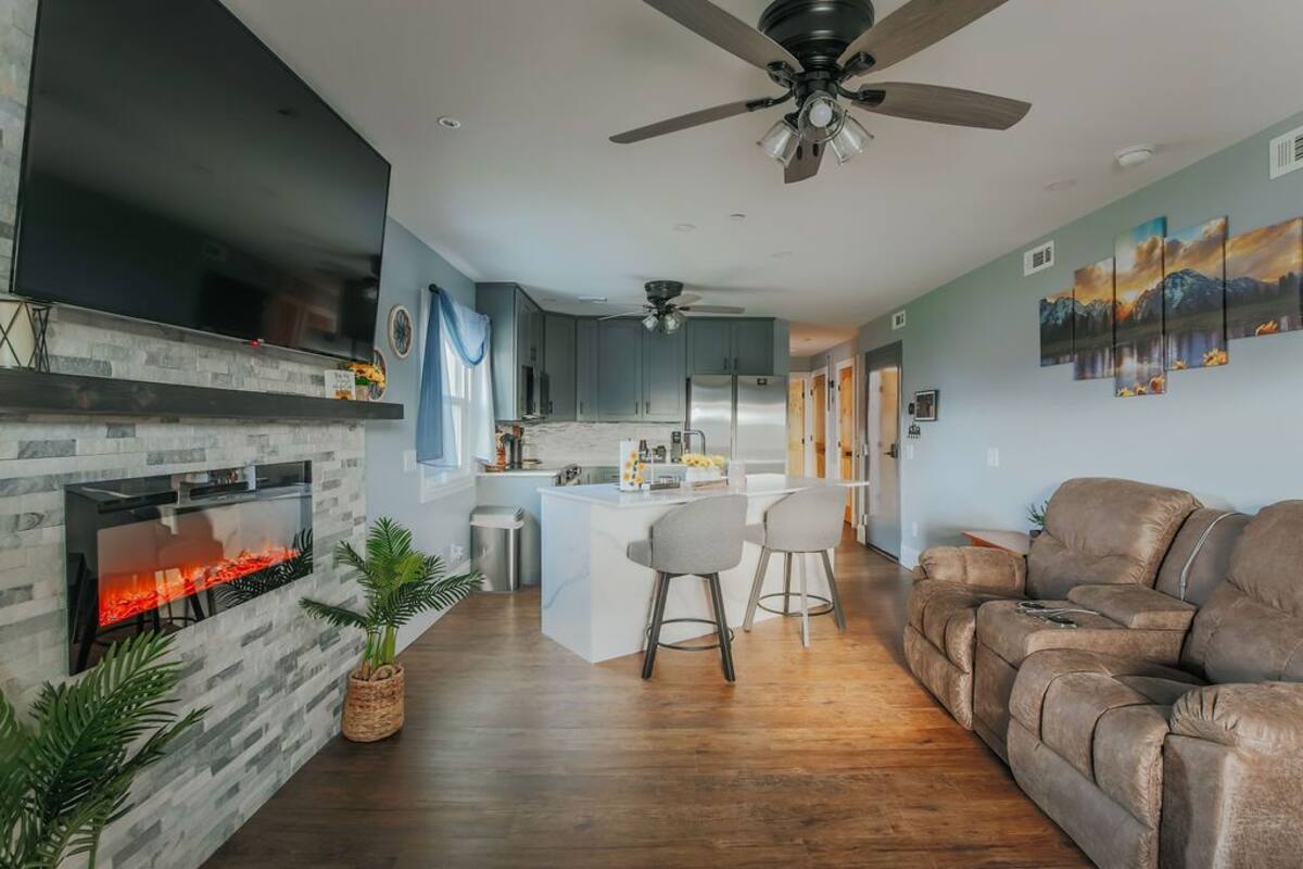 Een moderne woonkamer met een open haard, een bank en een eethoek met stoelen.