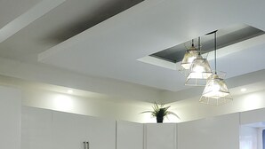 Cozinha moderna com armários brancos, ilha central, fogão e micro-ondas.