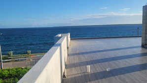 Um deck de madeira com guarda-corpo, dando vista para a água.