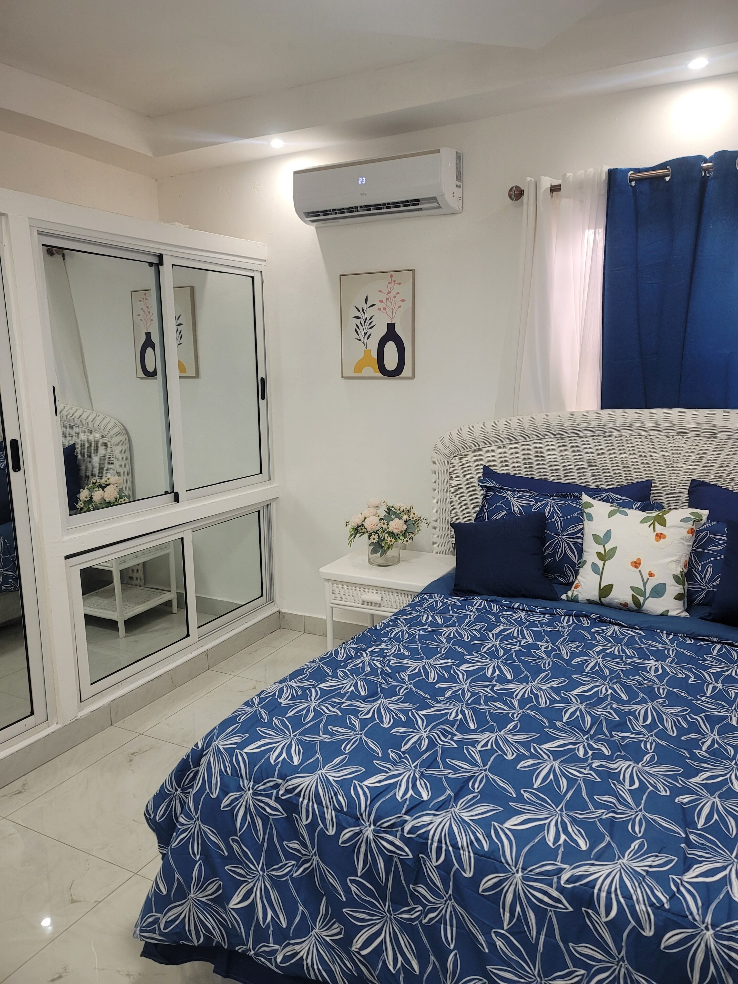 Un dormitorio con cama, armario, espejo y aire acondicionado.