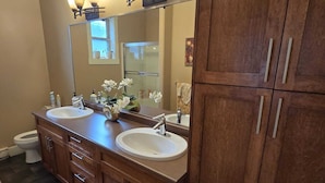 A bathroom with two sinks, a large mirror, and wooden cabinets.
