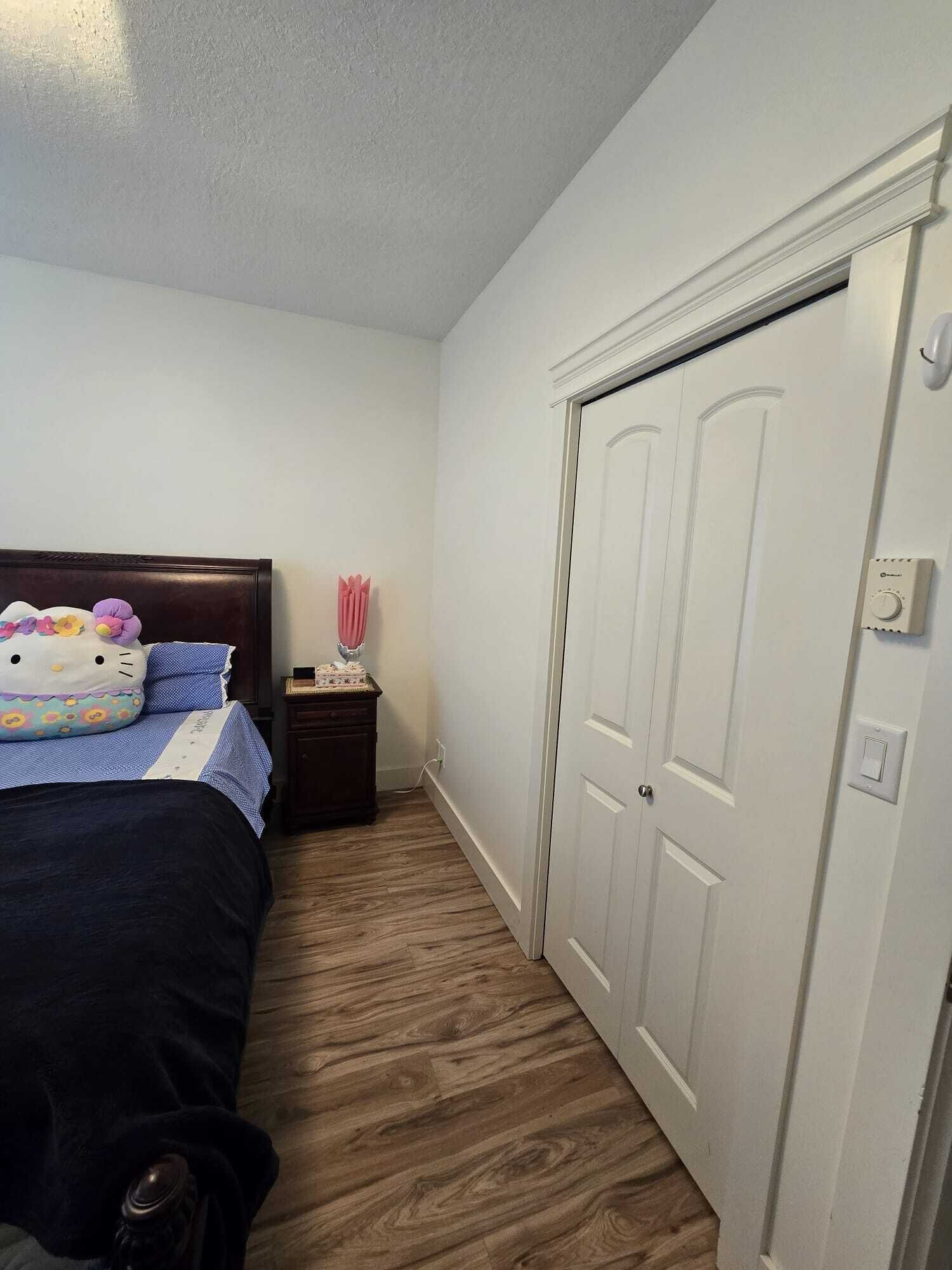 A bedroom with a bed, a nightstand, and a white door.