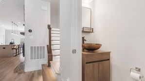 Et moderne badeværelse med et trækommode, en stor skålhåndvask og et skilt med teksten 'WASH YOUR HANDS'.