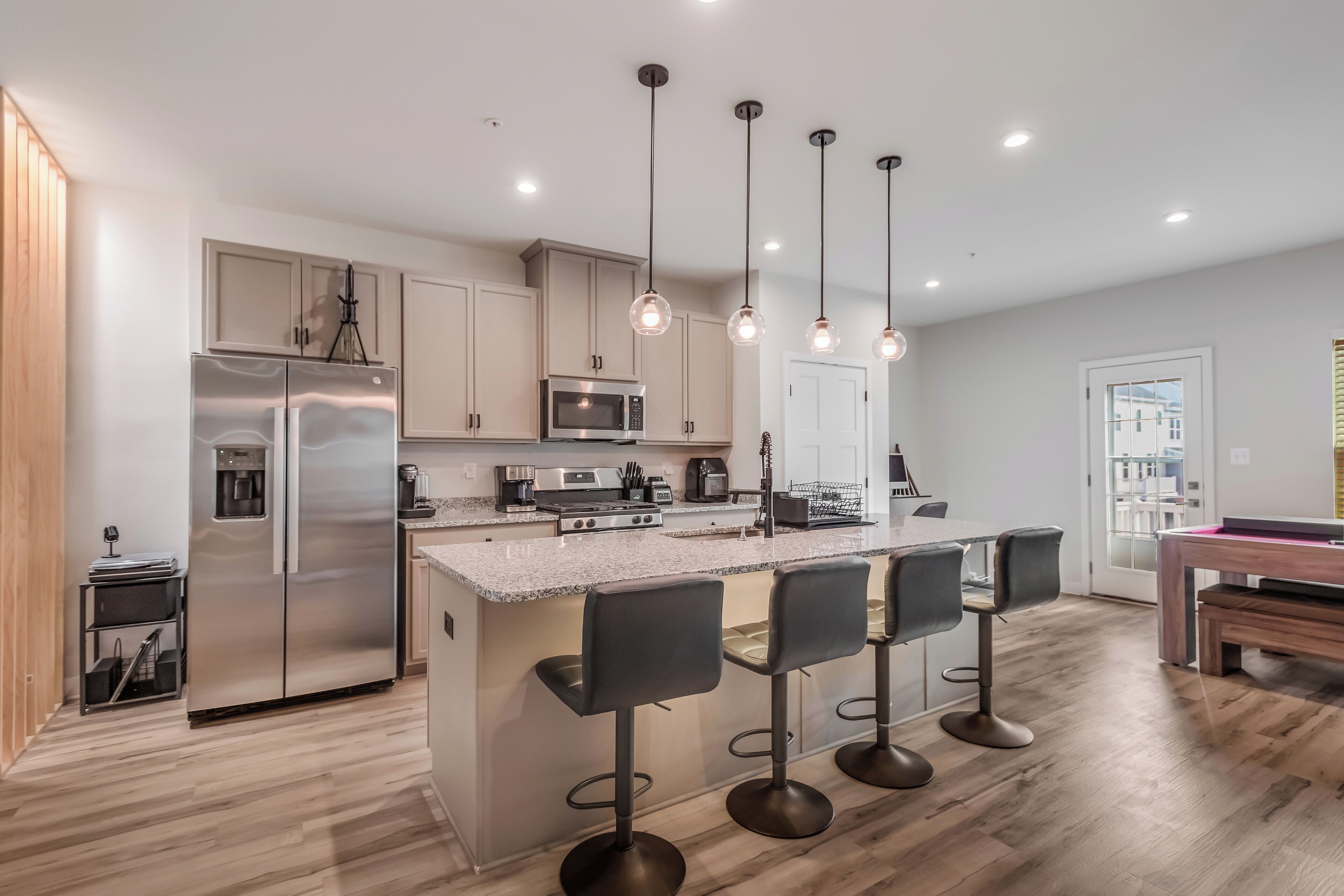 A modern kitchen with a central island, stainless steel appliances, and pendant lighting.