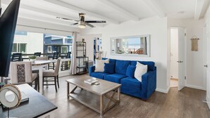 Una sala de estar amplia con un sofá azul, una mesa de centro y un comedor con sillas y una mesa.