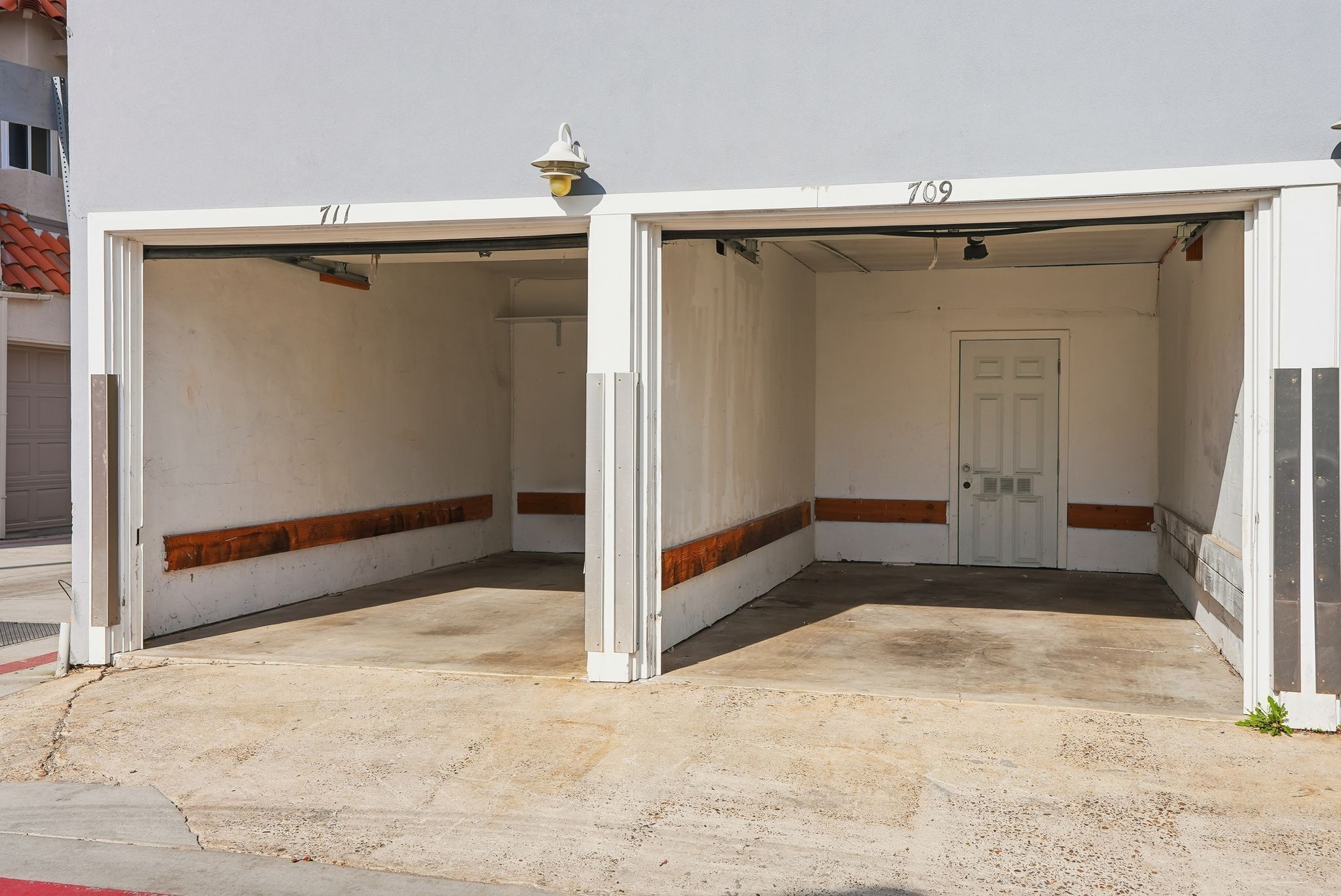 L’entrée d’un parking, avec deux portes de garage ouvertes, numérotées 711 et 709, et une porte blanche au centre.