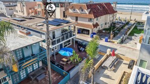 Un área residencial costera con casas modernas, un patio con mobiliario exterior y vista al océano.