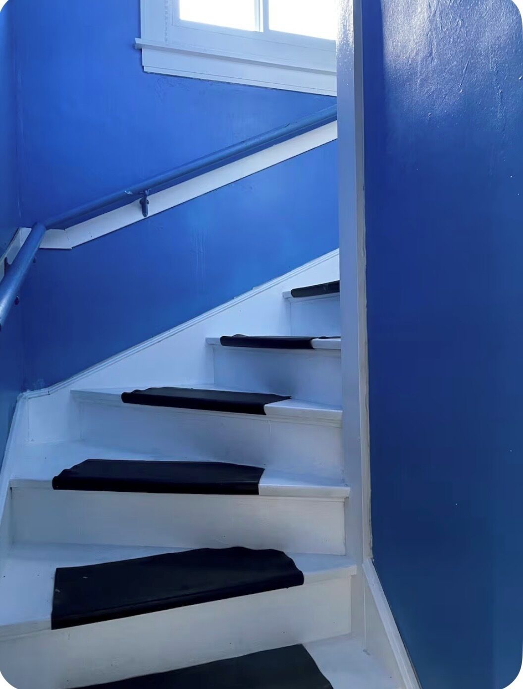 Eine Treppe mit blauen Wänden und weißen Stufen.