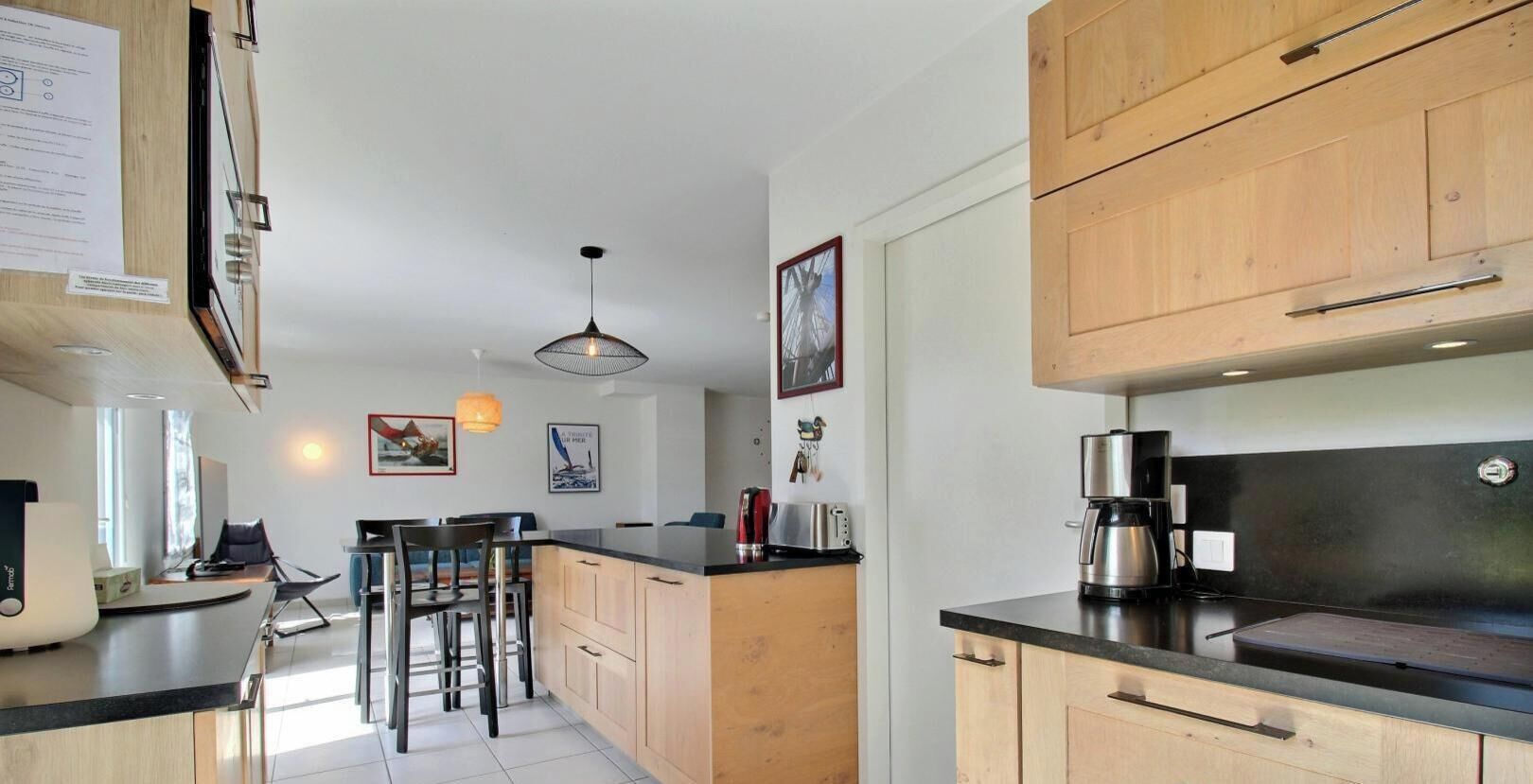 A modern kitchen with wooden cabinets, a black countertop, and a coffee maker.