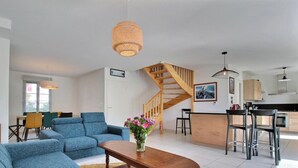 Ein geräumiges Wohnzimmer mit einem blauen Sofa, einem Holztisch und einer Treppe, die in einen Küchenbereich führt.