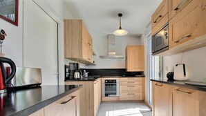Eine moderne Küche mit Holzausstattung, Edelstahlgeräten und einer schwarzen Arbeitsplatte.