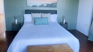 A neatly made bed with white linens and a teal pillow, flanked by two bedside tables with small potted plants. - Fabulous 4-bedroom house with AC in charming Bog Walk (Bog Walk)