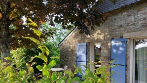 Un bâtiment en pierre doté d’un petit patio, d’une table et de chaises.