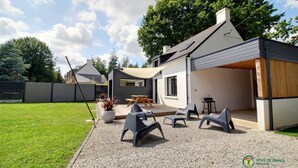 Una casa moderna con patio, arredi da esterno e barbecue.