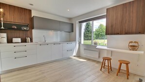 Una cucina moderna con mobili bianchi, forno a incasso e finestra con vista su un giardino.