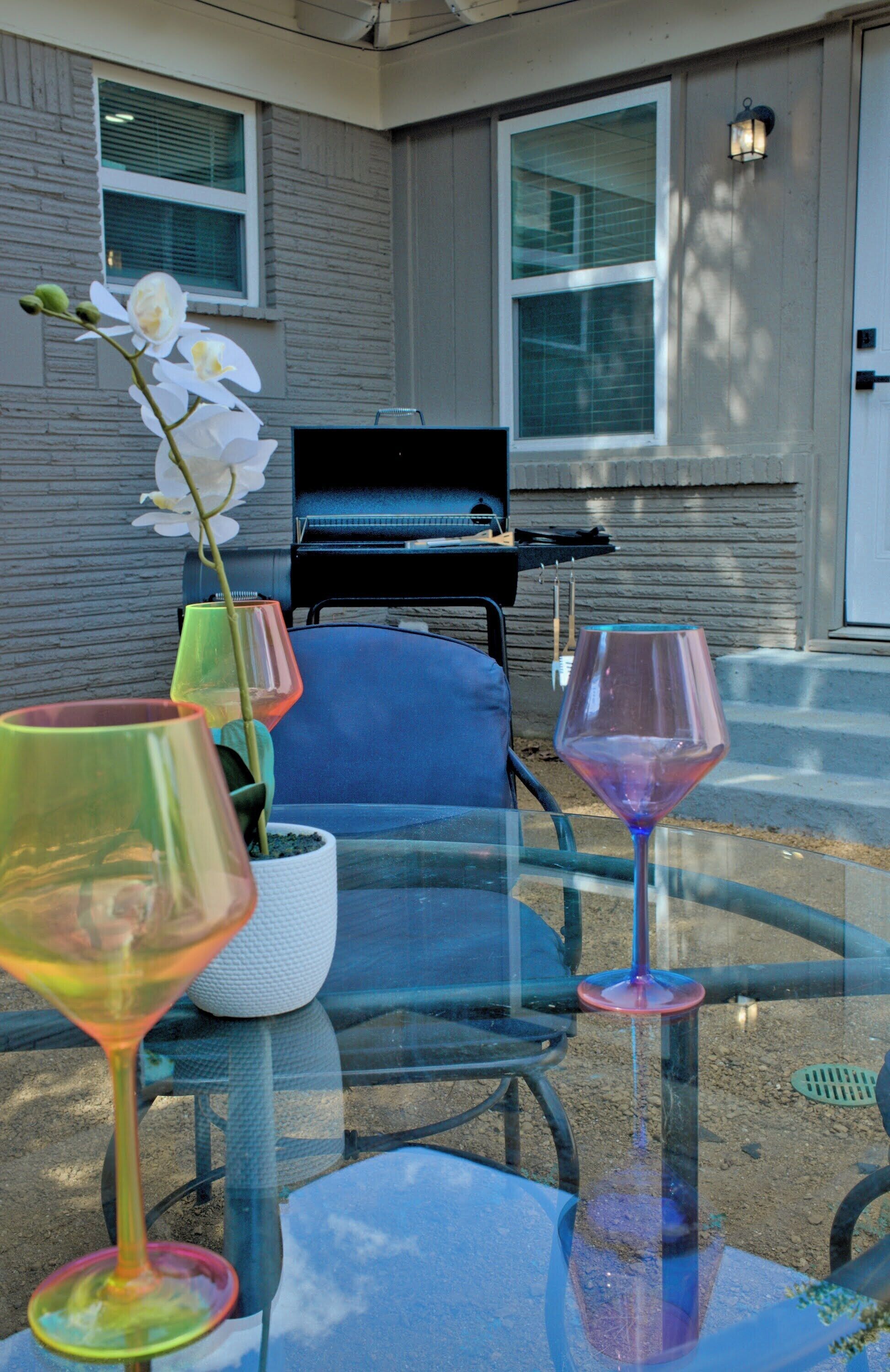 A glass table with three wine glasses and a potted orchid.