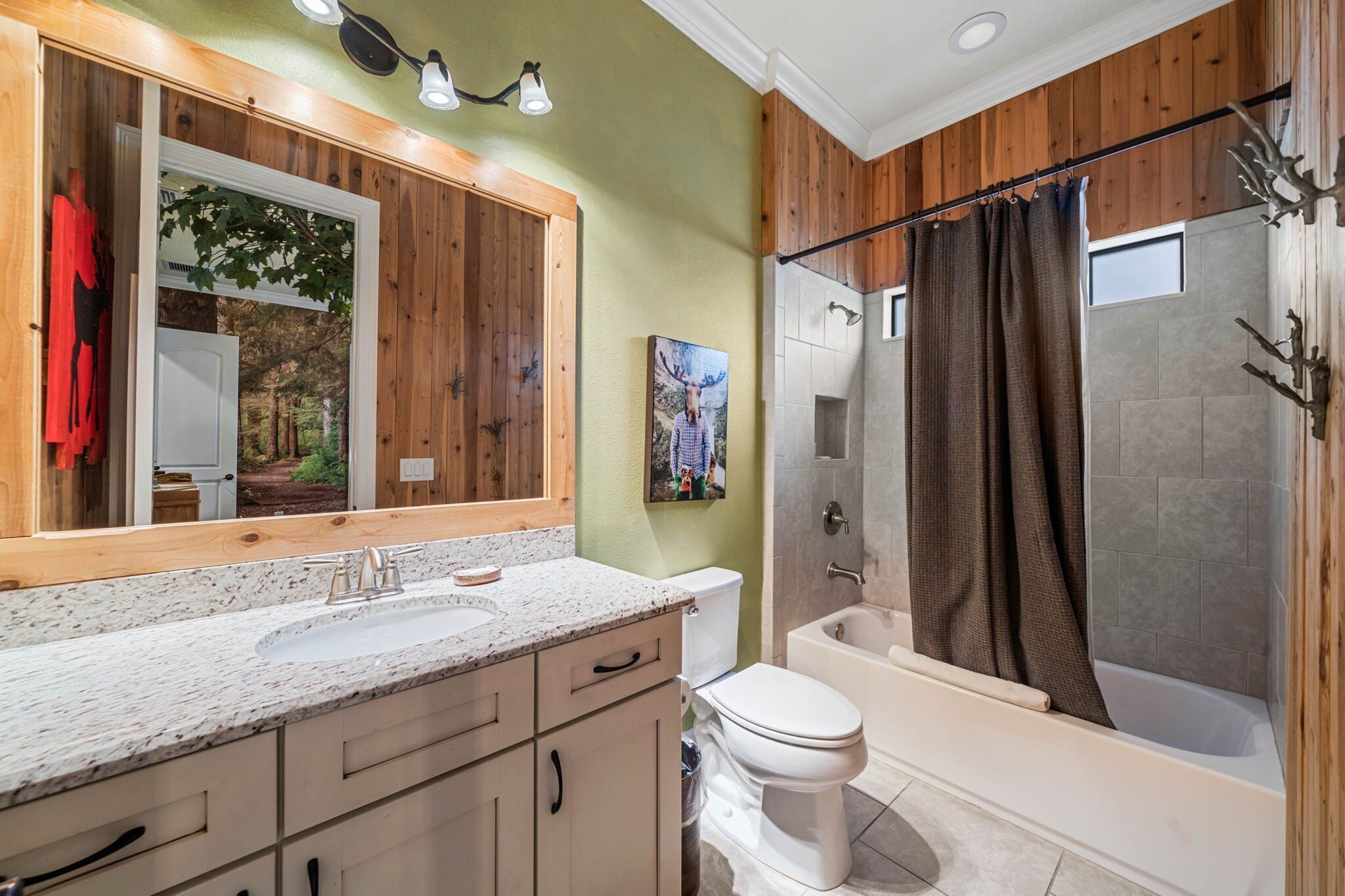 A bathroom with a large mirror, a sink, a toilet, and a bathtub.