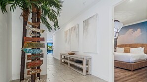 Ein Flur mit einem hölzernen Wegweiser, einem Korbbett und einer weißen Wand mit Wandgemälde.