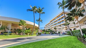 A hotel with a modern design, featuring a central courtyard with palm trees and a well-maintained lawn. - Lovely 2bd in Kihei, paradise awaits! (Kihei)