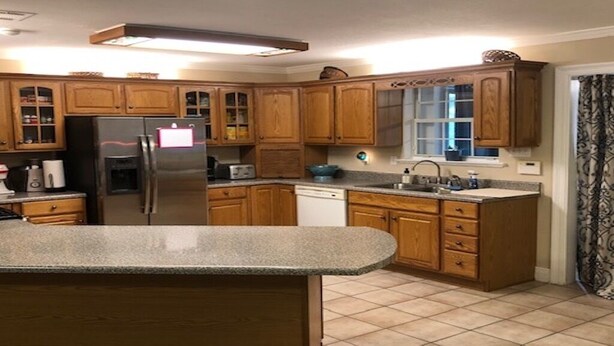 Una cocina con armarios de madera, encimera de granito, refrigerador de acero inoxidable y lavavajillas.