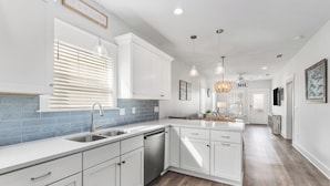 A modern kitchen with white cabinets, a stainless steel sink, and a dishwasher. - NEW LISTING! Special Sunset is steps to beach, hot tub, fenced backyard and pet friendly! Sleeps 6 (Mexico Beach)