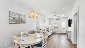 A modern dining area with a round table, chairs, and a hanging light fixture. - NEW LISTING! Special Sunset is steps to beach, hot tub, fenced backyard and pet friendly! Sleeps 6 (Mexico Beach)