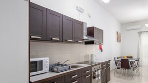 Una cocina moderna con armarios oscuros, un refrigerador blanco, un microondas y una zona de comedor con una mesa y sillas.