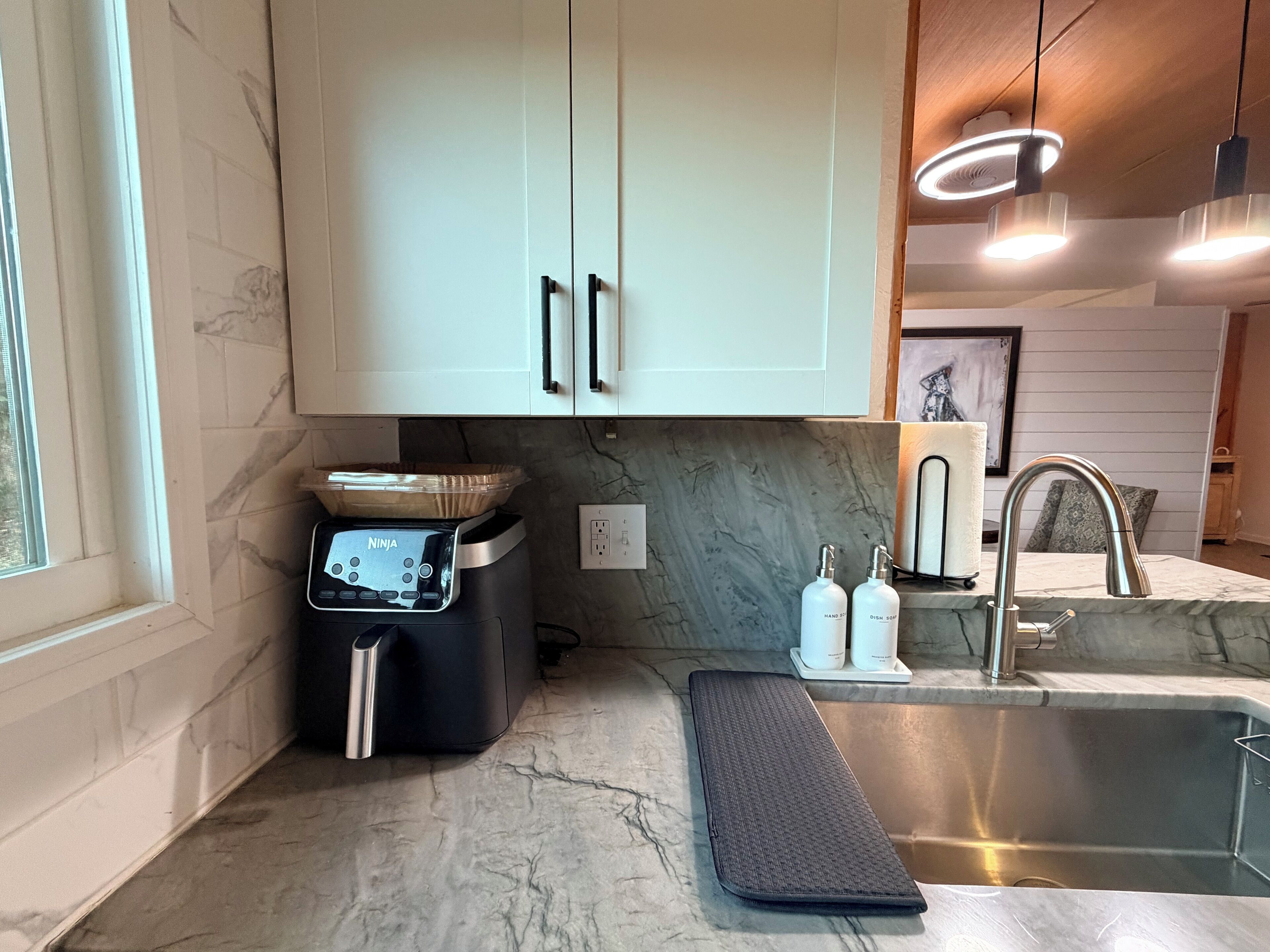 Una cocina moderna con armarios blancos, horno empotrado, lavabo y encimera con tapete.