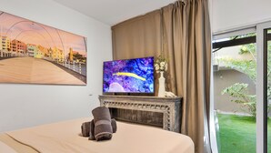 Ein Hotelzimmer mit Bett, Fernseher, Kamin und Blick auf einen Garten.