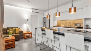 Eine moderne Küche mit Kochinsel, Barhocker, Pendelleuchten und einem eingebauten Backofen.