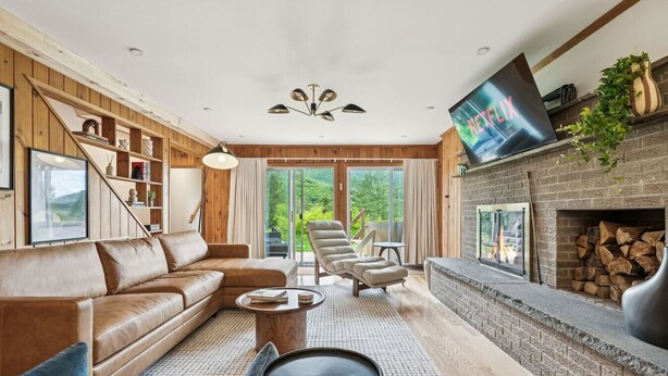 A modern living room with a leather sofa, a fireplace, and a TV mounted on the wall. - Mtn House w/ Hot Tub & Sauna @ Scribners, Sleeps 4 (Tannersville)